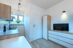 a white kitchen with a sink and a tv at Apartamenty Bałuty PARK in Łódź +5 photos