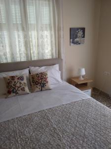 um quarto com uma cama com almofadas e uma janela em Paraskevi's House em Argos