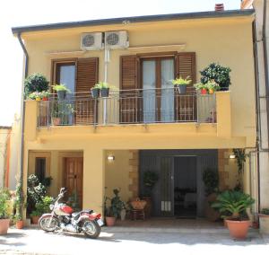 una moto parcheggiata di fronte a una casa con piante in vaso di Piccolo Sole d'oro - appartamenti a Calatafimi