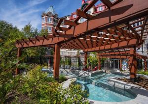a wooden pergola with a swimming pool in a garden at Sommet Des Neiges in Mont-Tremblant