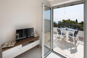 a living room with a television and a table with chairs at Dolores Apartments in Petrovac na Moru