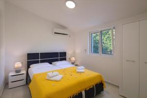 a bedroom with a yellow bed with towels on it at Dolores Apartments in Petrovac na Moru