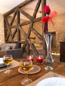 a table with wine glasses and a vase with a flower at Les Arcades in Sarlat-la-Canéda