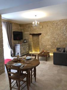 uma sala de estar com uma mesa e uma parede de pedra em Les Arcades em Sarlat-la-Canéda