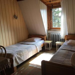 ランツコロナにあるLeśny Ogródのベッドルーム1室(ベッド2台、窓、ラジエーター付)