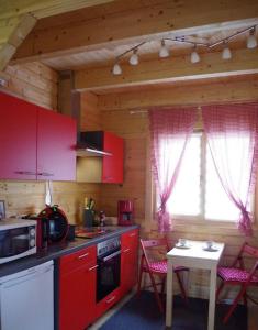 eine Küche mit roten Schränken und einem Tisch mit Stühlen in der Unterkunft Idyllische Holzhütte mit Wasserzugang und Sauna in Ketzin