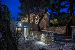 a house with a stone wall and a table and chairs at Dolores Apartments in Petrovac na Moru
