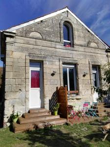 een klein stenen huis met een witte deur en stoelen bij Le Grenier in Les Ageux