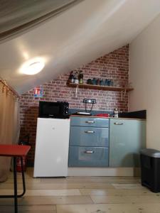 uma cozinha com um frigorífico branco e uma parede de tijolos em Le Grenier em Les Ageux