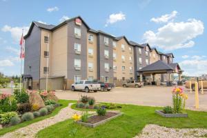 un grande edificio con auto parcheggiate in un parcheggio di Devonian Hotel and Suites a Fox Creek