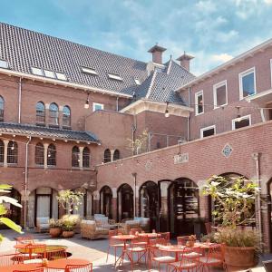 a courtyard with tables and chairs in front of a building at The Anthony Hotel in Utrecht