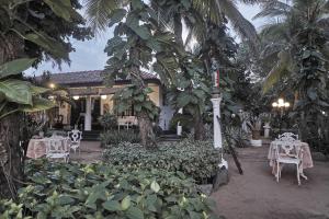 a patio with white tables and chairs and palm trees at The Icebear Guesthouse in Negombo