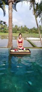a woman in a bikini sitting on a raft in the water at Bali Harmony Villa in Ubud