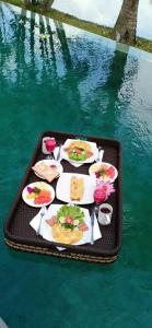 a tray with plates of food on a table in the water at Bali Harmony Villa in Ubud