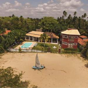 a small sail boat on the beach in front of a house at RANCHO GOSTOSO POUSADA in São Miguel do Gostoso