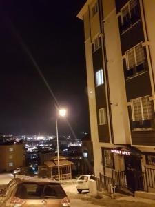 トラブゾンにあるNURALP APART OTEL - Trabzonの通灯付き建物の隣に停車する車