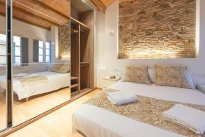a bedroom with two beds and a stone wall at Bravissimo Plaça dels Raïms in Girona