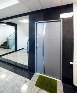 a glass elevator door in a lobby with a green rug at STOP Apartment in Suwałki