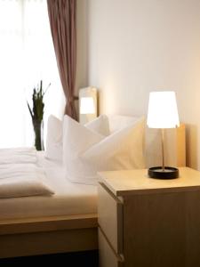 una camera da letto con un letto con una lampada e una finestra di Apartmenthaus Feuerbach a Lipsia