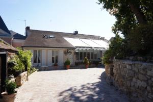 a house with a stone wall and a brick driveway at La Gallina Bianca in Feucherolles