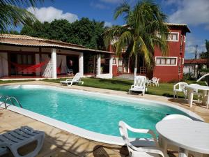 a swimming pool with a table and chairs and a house at RANCHO GOSTOSO POUSADA in São Miguel do Gostoso