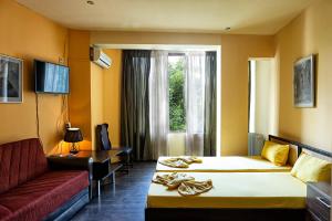 プロブディフにあるHotel Trakart Residenceのベッド2台とソファが備わるホテルルームです。