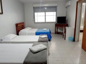 a hotel room with two beds and a television at Pousada Terra Sul in Porto Alegre