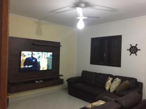 Casa de Temporada Juquehy في جوكاي: غرفة معيشة مع أريكة وتلفزيون بشاشة مسطحة