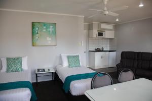 een woonkamer met 2 bedden en een bank bij BKs Palm Court Motor Lodge in Gisborne
