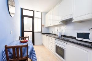 a kitchen with white cabinets and a table and a chair at Center Santa Cruz de Tenerife Parking in Santa Cruz de Tenerife