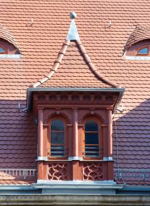 ein orangefarbenes Kacheldach mit drei Fenstern darauf in der Unterkunft Apartmenthotel Quartier M in Leipzig