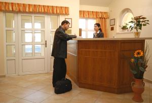 Hotel Bavaria في Abda: رجل يقف عند كاونتر أمام امرأة