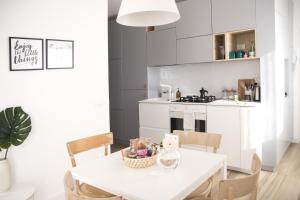 biała kuchnia z białym stołem i krzesłami w obiekcie Appartamento 14 10 w mieście Marcigliana