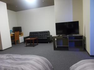 um quarto de hotel com um sofá e uma televisão em Route Inn Grantia Komaki em Komaki