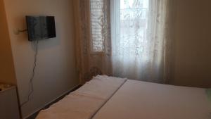 a bedroom with a bed with a tv and a window at Gunay Pansiyon Antalya in Antalya