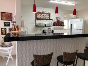 Una cocina con una encimera con sillas y un refrigerador. en Le Bon Vivant 307 B, en Arraial do Cabo