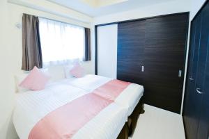 a bedroom with a large bed with pink pillows at momo premium 602 in Sapporo