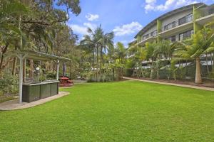 a grassy area with trees and a building at Flynns Beach Resort in Port Macquarie
