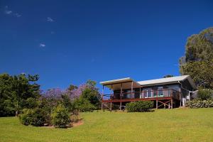 una grande casa su una collina con un campo verde di Afterglow Cottages a Bellingen