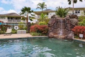 a swimming pool with a waterfall in front of a house at Plantations at Princeville #512 in Princeville