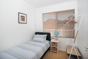 een slaapkamer met een bed en een raam bij Beach side holiday apartment in Batemans Bay