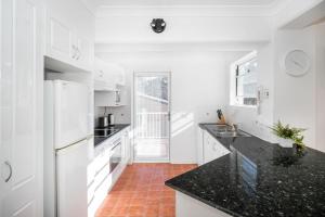 a kitchen with white appliances and black counter tops at Beach side holiday apartment in Batemans Bay