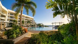 un complejo con piscina, palmeras y el océano en Vue Apartments Trinity Beach, en Trinity Beach