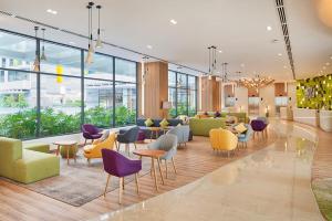 a lobby with colorful chairs and tables and windows at Holiday Inn & Suites Saigon Airport, an IHG Hotel in Ho Chi Minh City