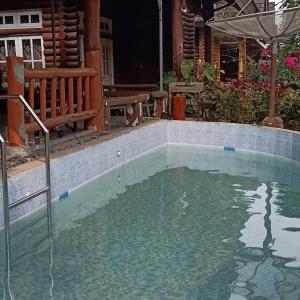 a pool of water with a bench and an umbrella at Vila Kota Bunga Private Pool in Puncak +36 photos