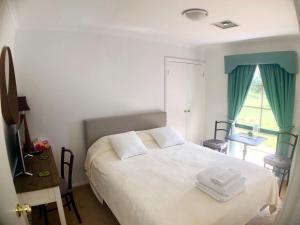 a bedroom with a white bed and a window at Melbourne Garden Bed and Breakfast in Melton