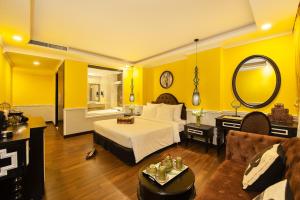 1 dormitorio con paredes amarillas, 1 cama y 1 sofá en Adora Art Hotel en Ho Chi Minh