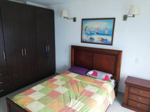 1 dormitorio con 1 cama y una pintura en la pared en Dpto Moderno Frente al Mar. Edf: Deymar 7mo Piso, en Tonsupa