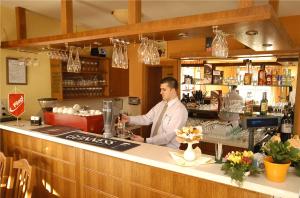 a man standing behind a counter in a bar at Hotel Bavaria in Abda