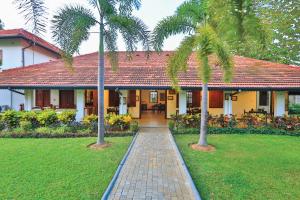 a house with two palm trees in front of it at Fox Jaffna by Fox Resorts - Boutique Heritage Luxury in Jaffna